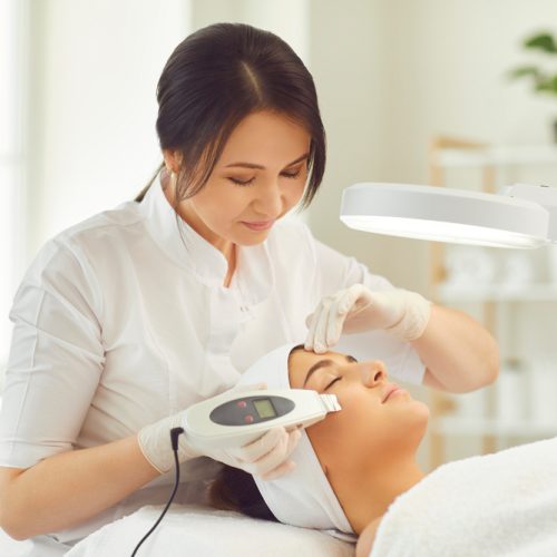 Smiling,Dermatologist,Making,Ultrasound,Apparatus,Facial,Cleaning,For,Young,Woman